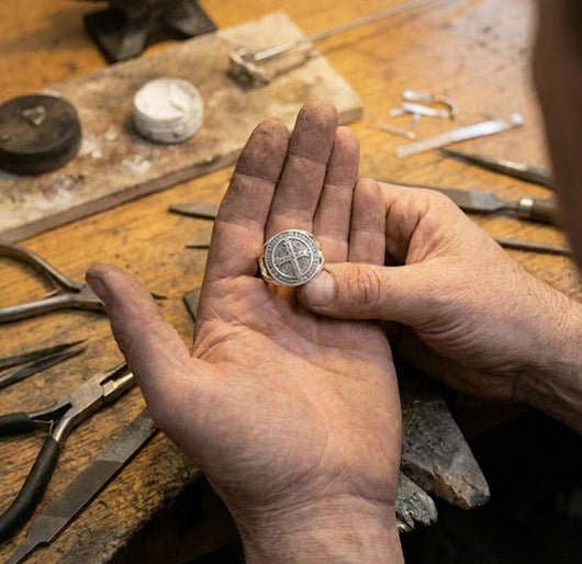 Hands holding a medal at a workbench