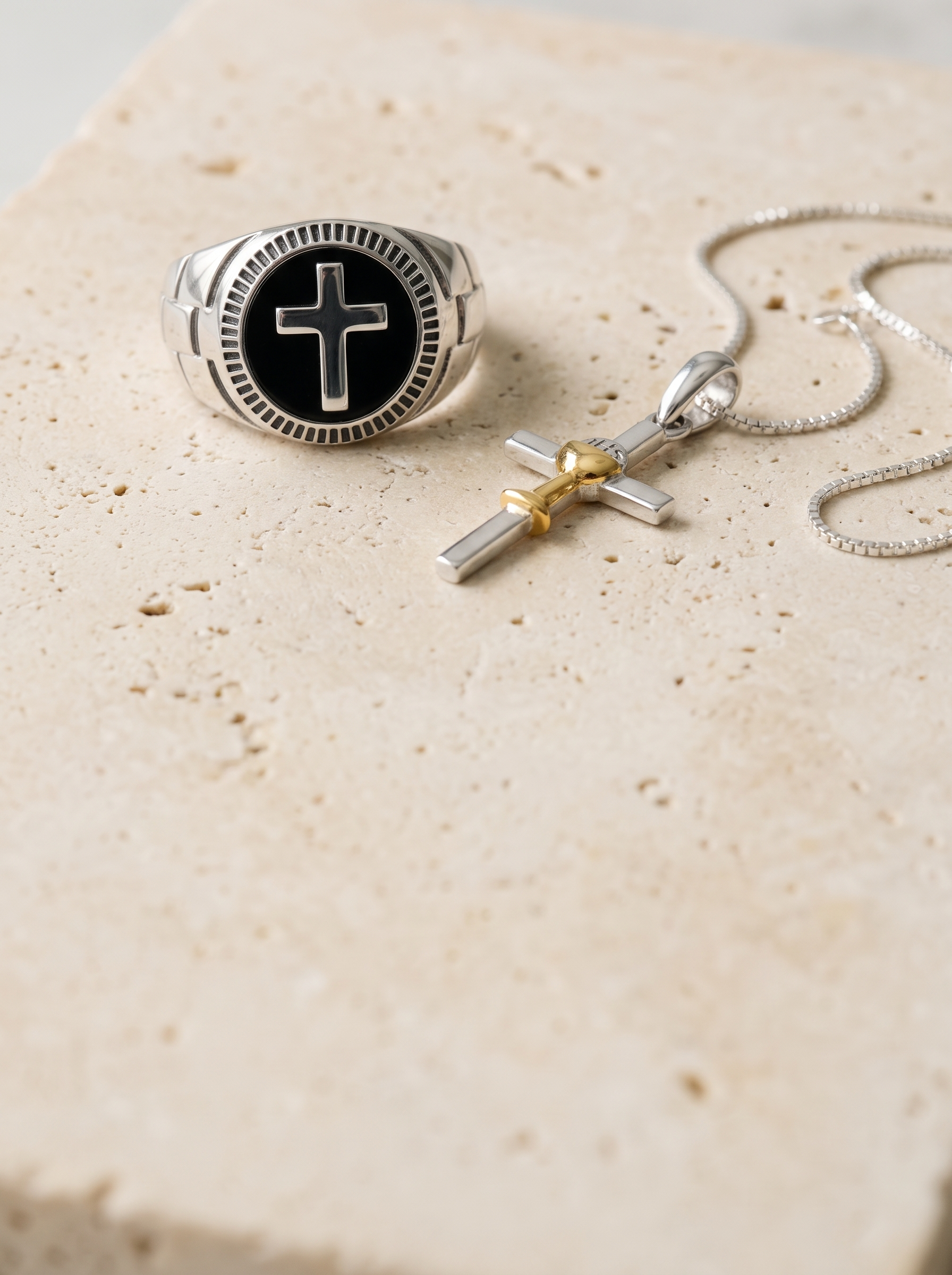 Men's onyx cross signet ring and chalice cross pendant on pale limestone, mobile banner