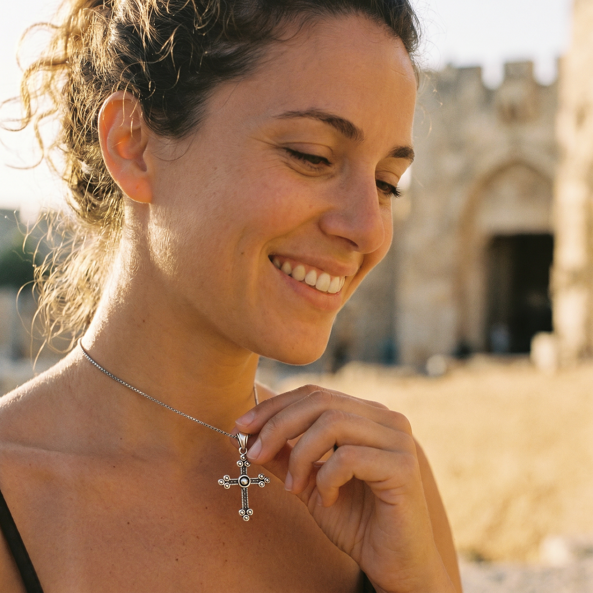 Smiling woman wearing a crucifix pendant necklace outdoors
