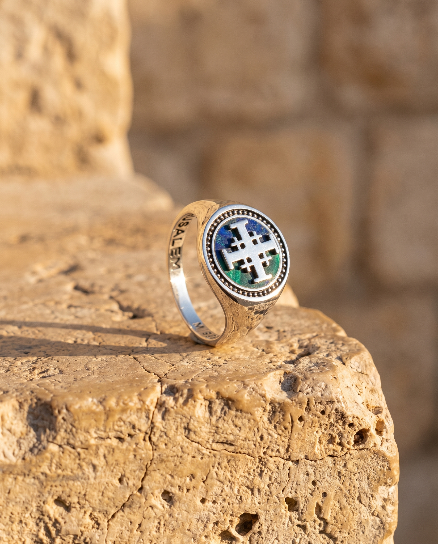 Jerusalem Cross ring with green enamel on a stone ledge